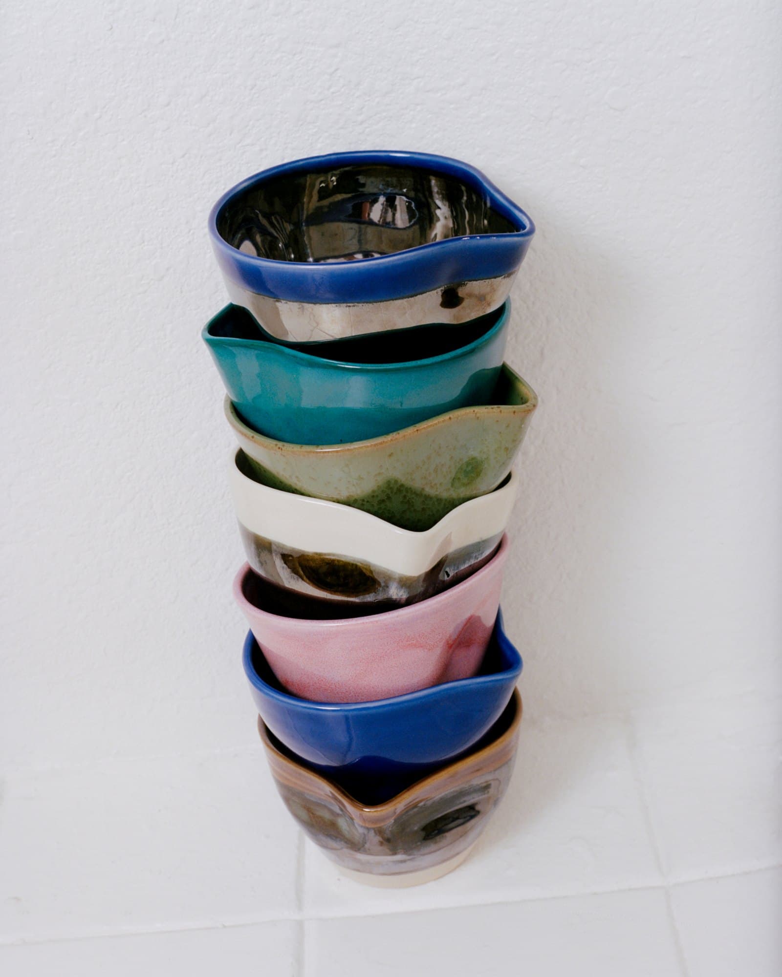 A stack of Studio Nia spouted bowls in many glazes