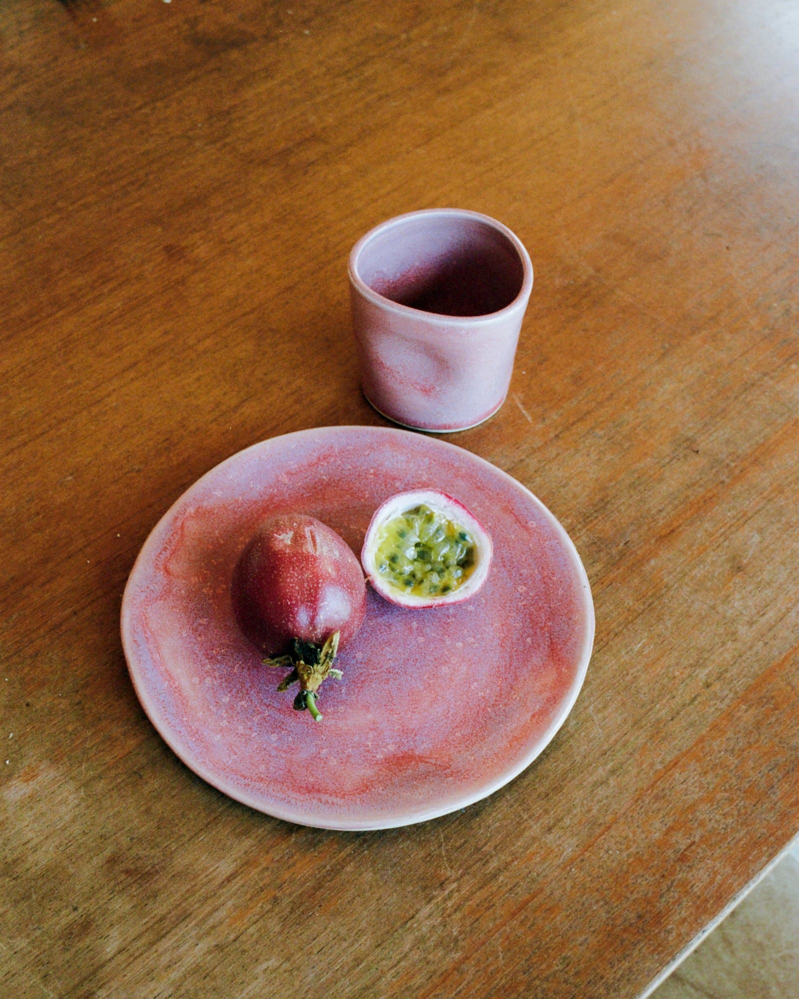 A pink Studio Nia plate and cup with passion fruit