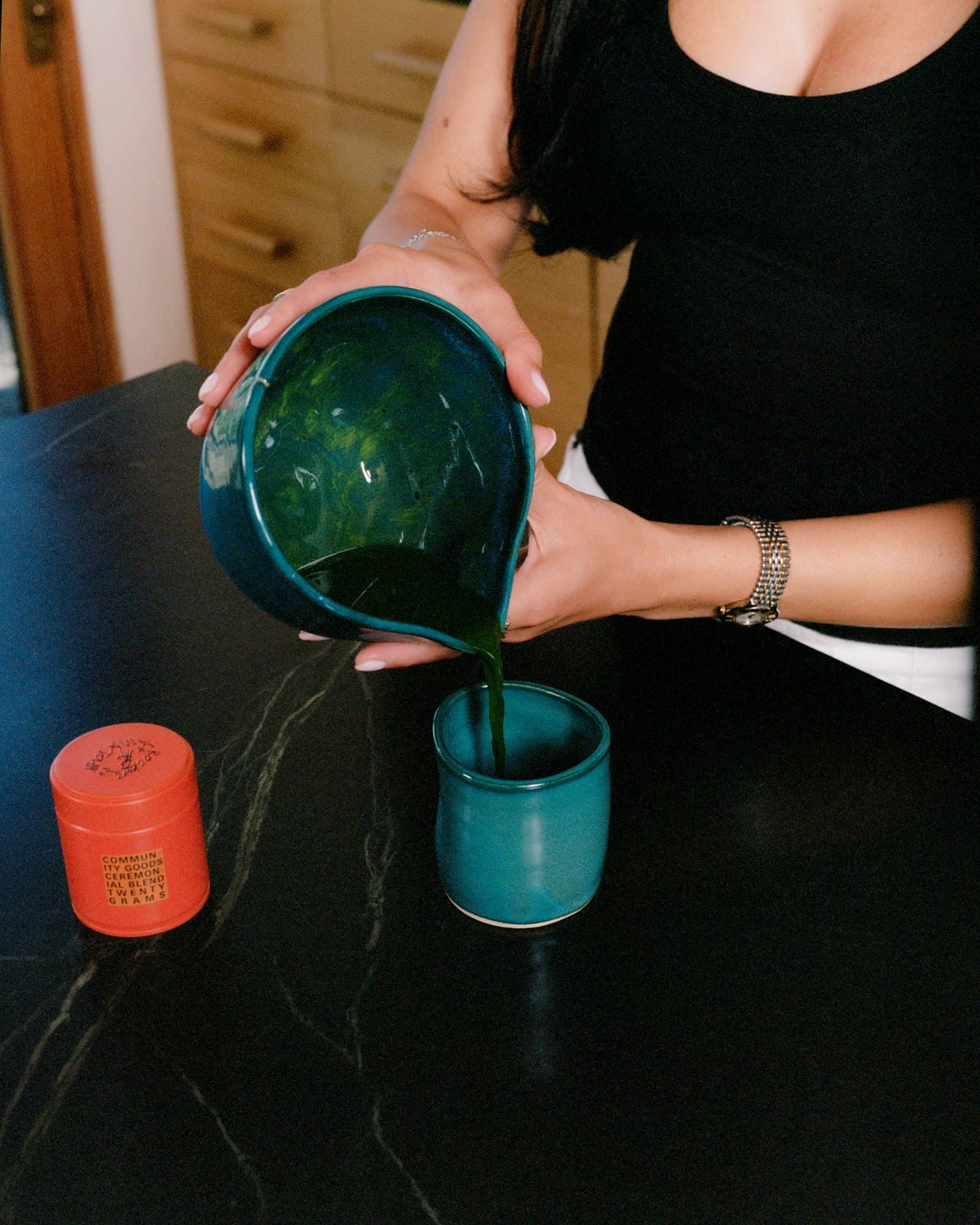 Matcha poured from a green Studio Nia bowl into a cup