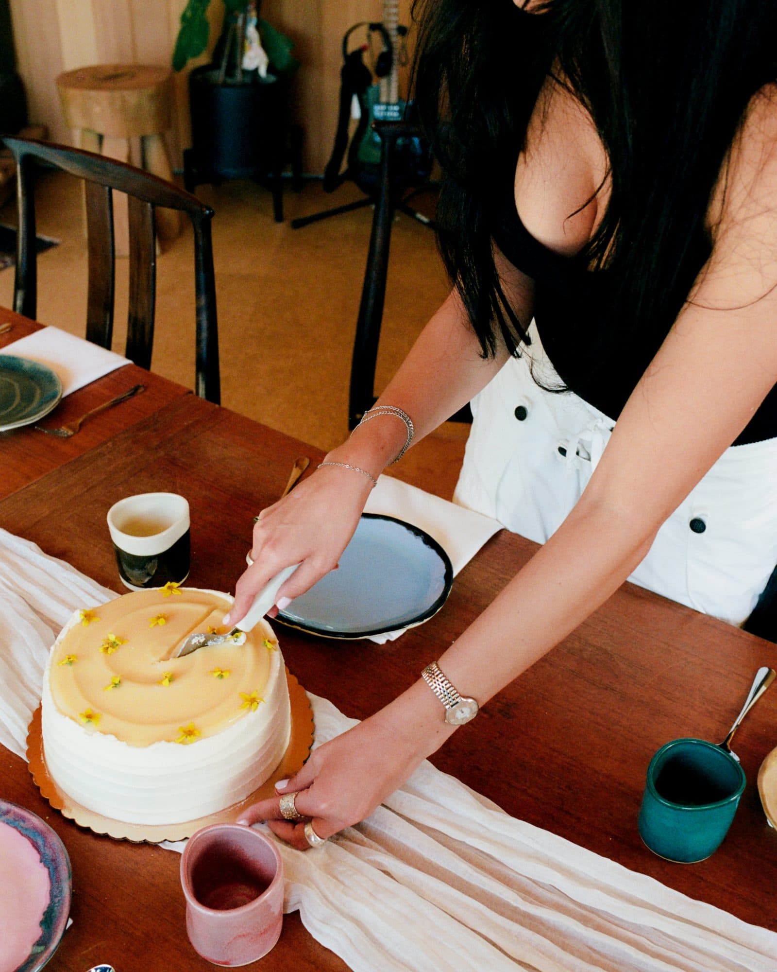 Daniella cutting a cake at a table set with Studio Nia ware