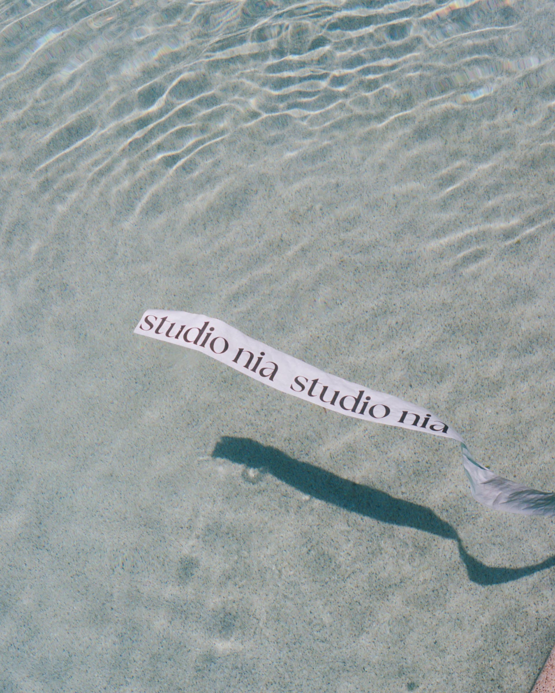 A studio nia ribbon floating over the water of a sunlit pool